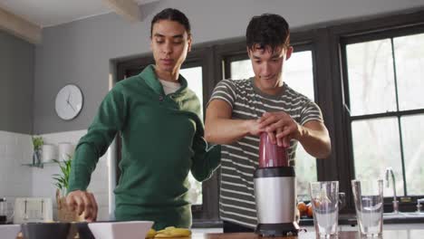 Happy-diverse-male-couple-making-healthy-drink-together-in-kitchen