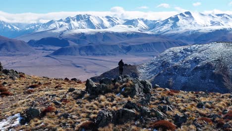 Breathtaking-aerial-view-of-snowy-mountain-peaks-and-person-standing-on-summit