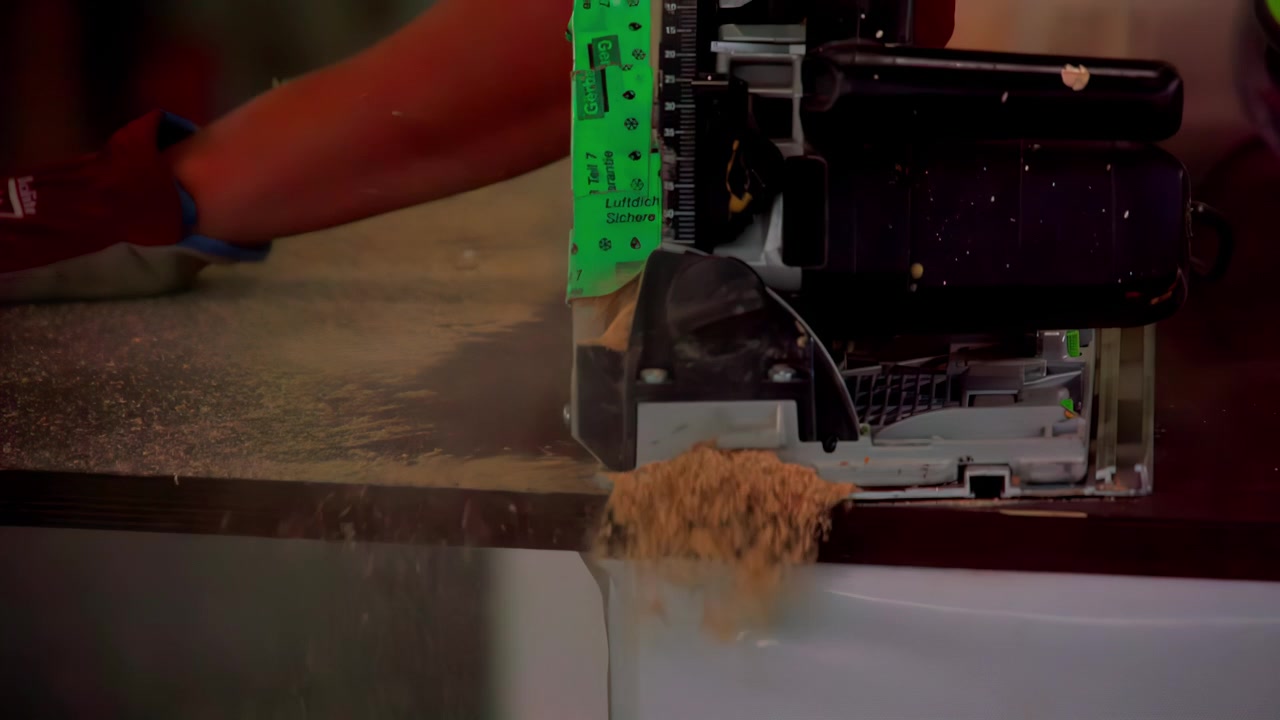 Handwerker schneidet Holzbrett mit einer Oberfräse in einer Werkstatt.