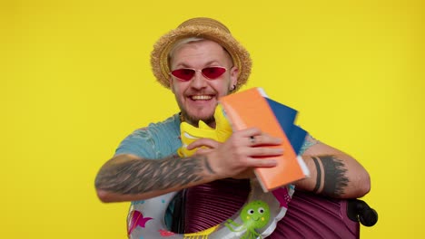 joyful bearded stylish traveler tourist man celebrating, dancing holding passport, tickets, luggage