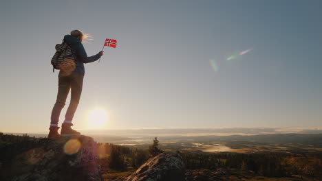 Ein-Reisender-Mit-Der-Norwegischen-Flagge-In-Der-Hand-Trifft-Den-Sonnenaufgang-Auf-Dem-Gipfel-Des-Berges