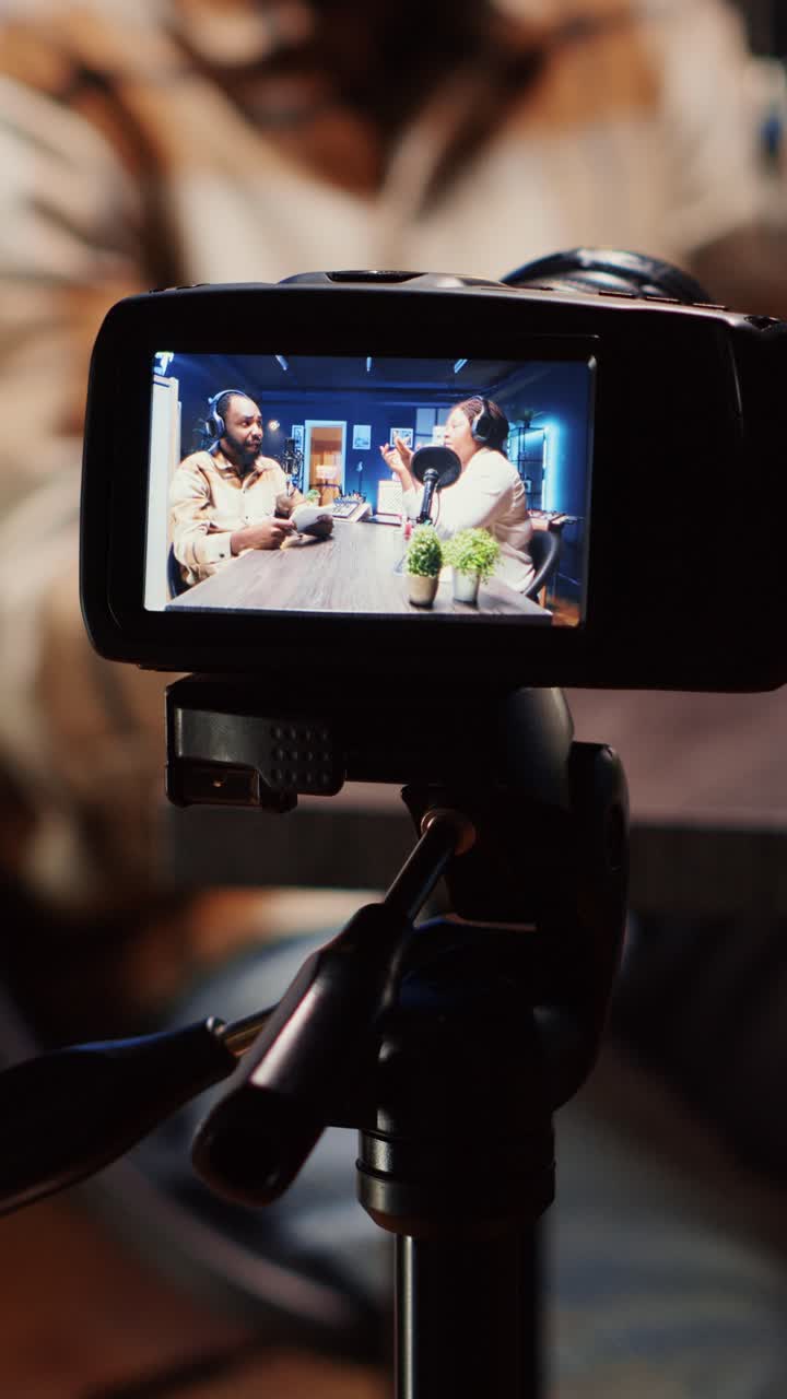 Podcastvært med vertikal video bruger smartphone på et stativ til at optage en gæst, der fortæller en spændende historie