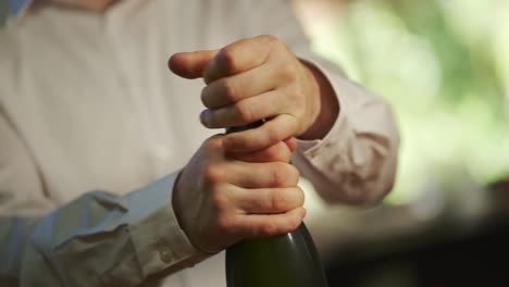 a man removes the cork and opens a bottle of champagne to celebrate