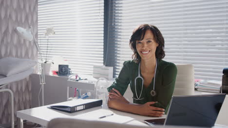 Retrato-De-Una-Doctora-Sonriente-Con-Estetoscopio-Sentada-Detrás-Del-Escritorio-En-La-Oficina