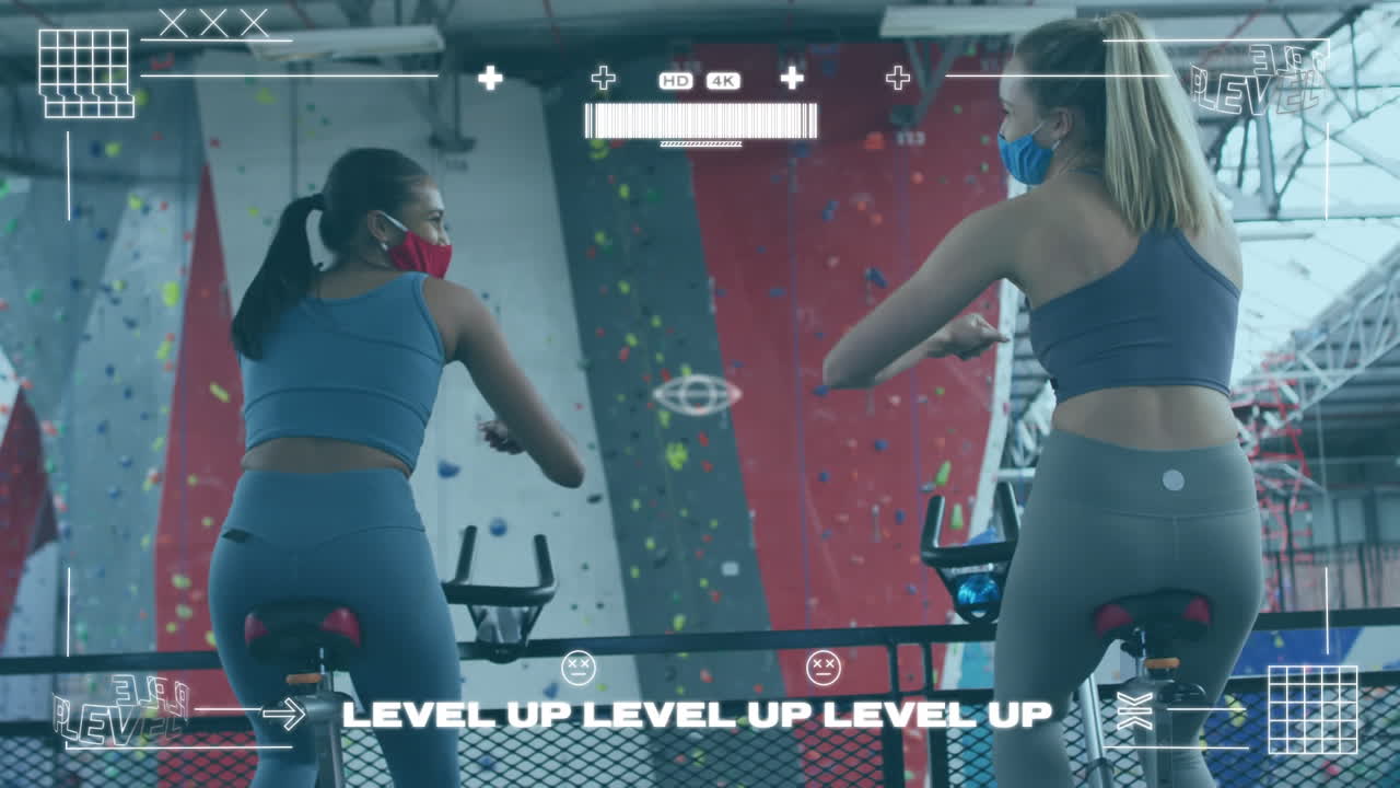 체육관에서 정지 자전거에서 운동하는 동안 팔꿈치를 만지는 두 여성에 대한 게임 인터페이스