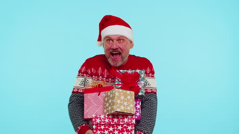 man in christmas red sweater, santa hat, smiling, holding many gift boxes new year presents shopping