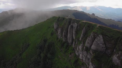 aerial shot moving forward over a mountain ridge with clouds rolling in