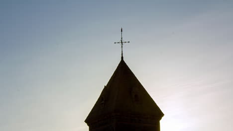 weathervane on top of a fortification roof while an airplane passes leaving a wake in the sky