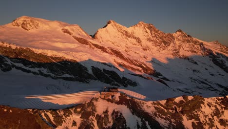 aerial panning shot of a mountain ridge lit by an orange light during a sunrise