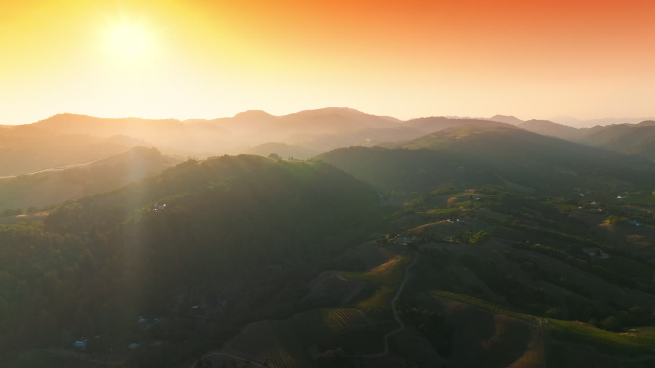 Picturesque green mountains of Napa, California, USA. Amazing vineyards from aerial perspective at setting sun. Orange sky at backdrop.