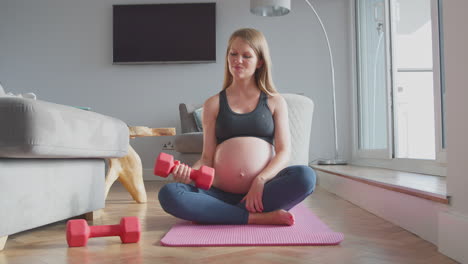 Schwangere-Frau-Trägt-Fitnesskleidung-Auf-Der-Matte-Und-Trainiert-Zu-Hause-Mit-Gewichten