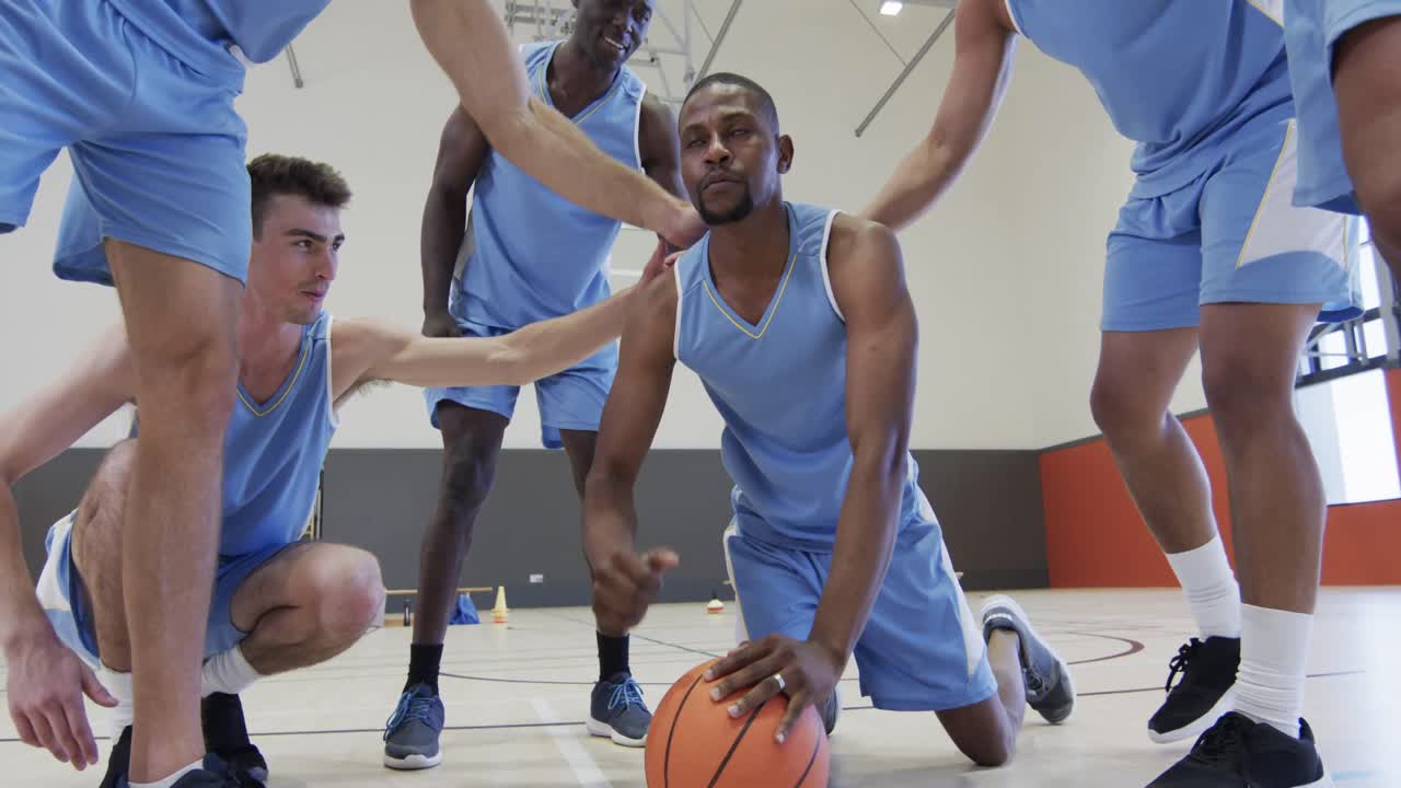 Diverse male basketball team training, congratulating player doing press ups on ball, slow motion