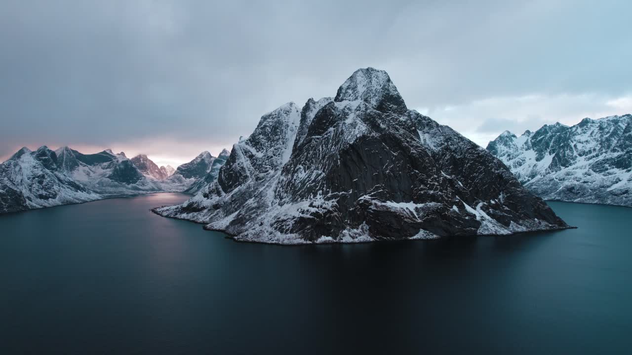 vista aérea de montañas nevadas en reine, islas lofoten, noruega al atardecer con nubes azul oscuro