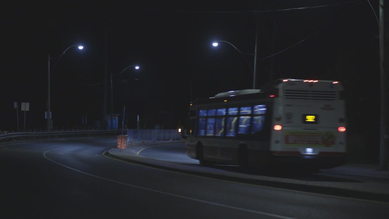 Passenger Bus Travelling On A Peaceful Street Road In Canada At Night - Medium Shot (Static)