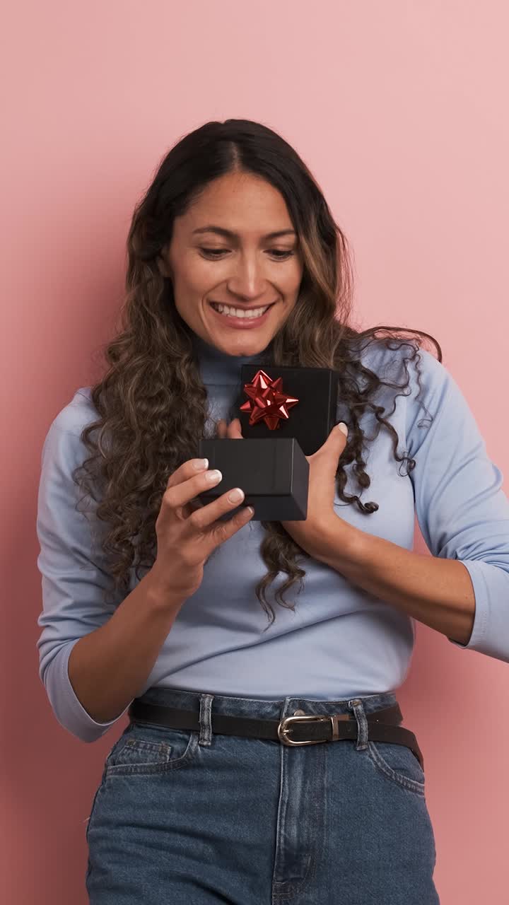 Woman opening a gift box and getting surprised. Vertical footage