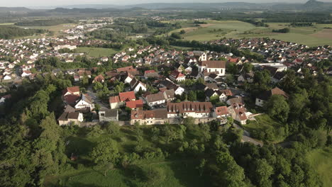 drone footage moving forward from the opposite side, focusing on the historic town of aach and its church tower, with a beautiful view of the surrounding landscape.