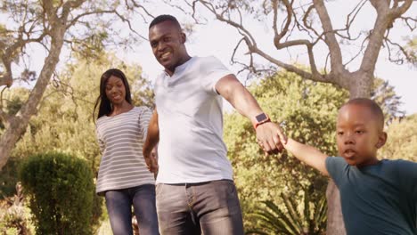 Vista-Lateral-De-Una-Familia-Feliz-Tomados-De-La-Mano-Y-Caminando.