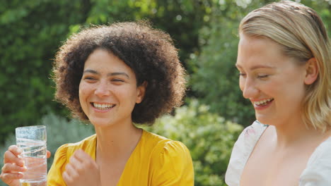 Three-Female-Friends-Sitting-Outdoors-In-Summer-Garden-At-Home-Relaxing-And-Talking