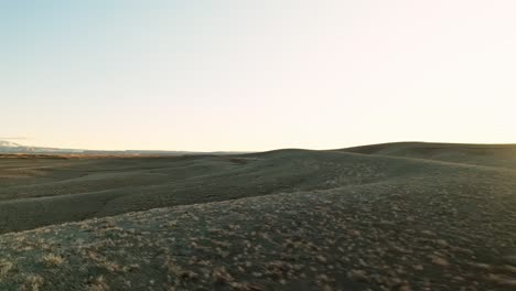 aerial tracking of an suv driving through an empty desert road at sunset, vast open landscape