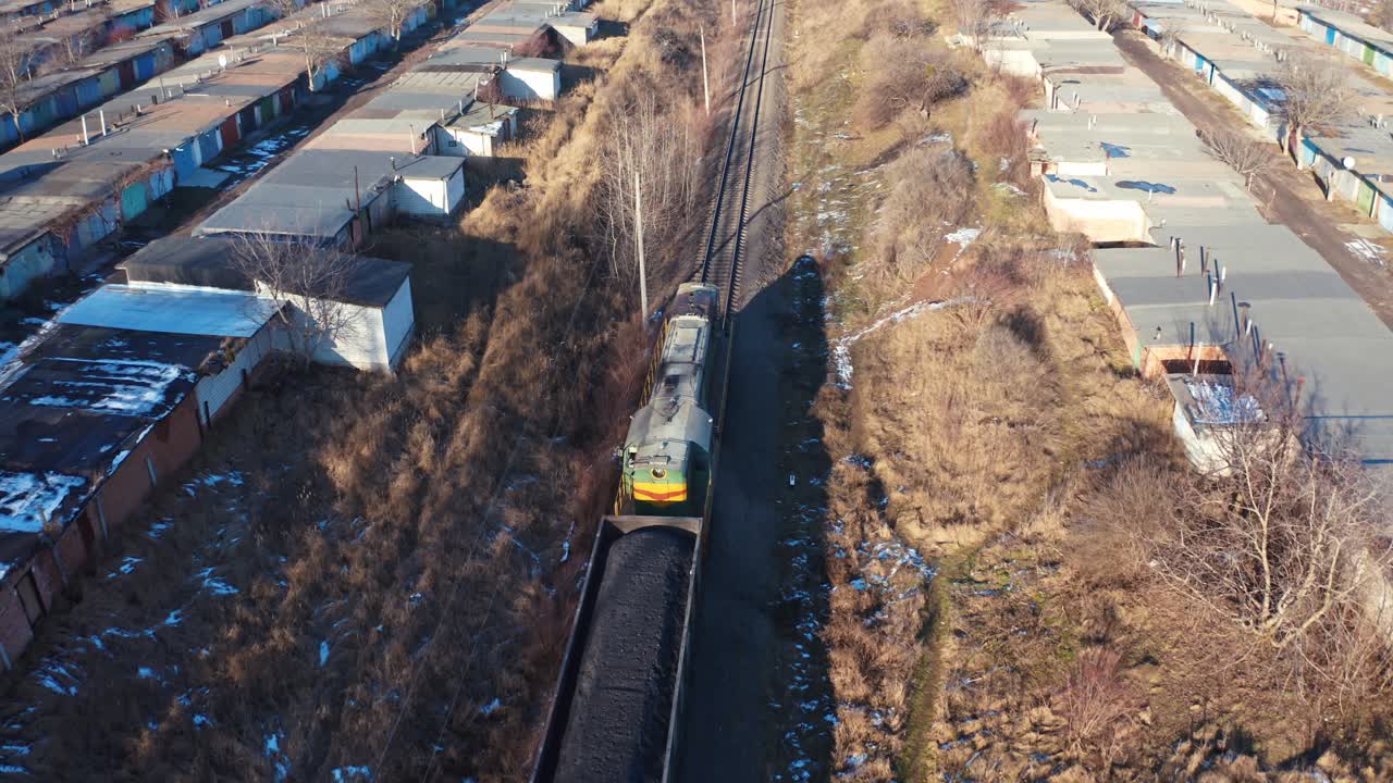 Cargo train on a railroad in sunny winter day. Top view on a freight train on the background of many garages from both sides. Aerial view.