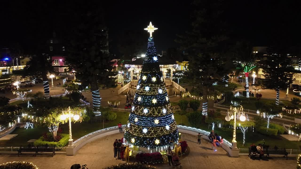 Tourists posing at Christmas tree in Jardín Principal de Tuxpan with Quiosco de Tuxpán in background
