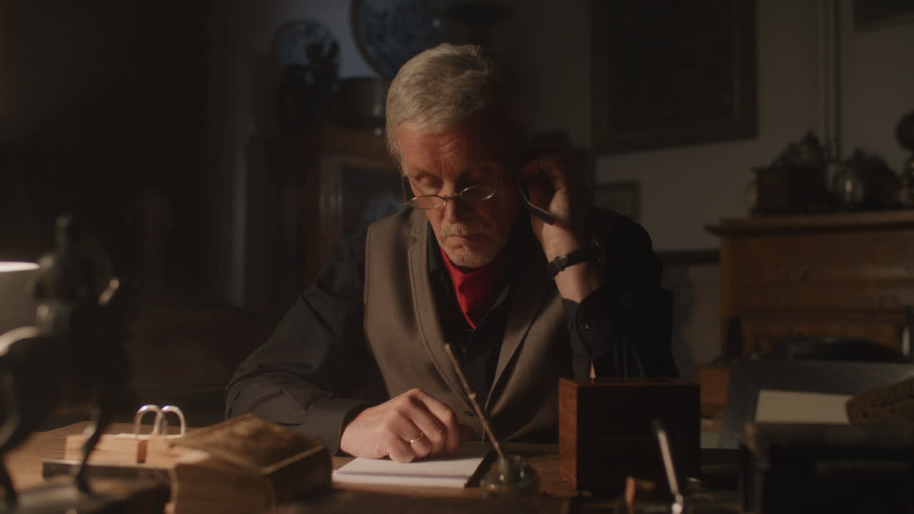 Older passionate man evaluates an old watch in his office at night