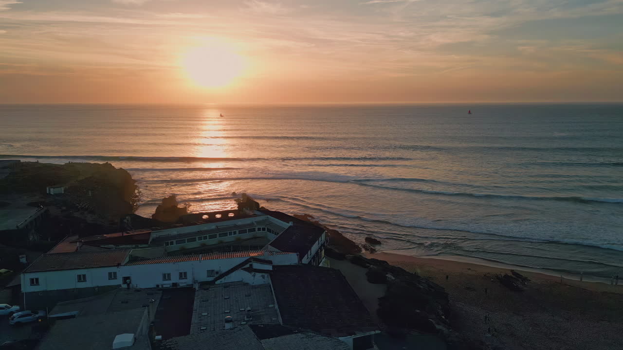 Spectacular golden sun setting down behind ocean horizon aerial. Waves washing