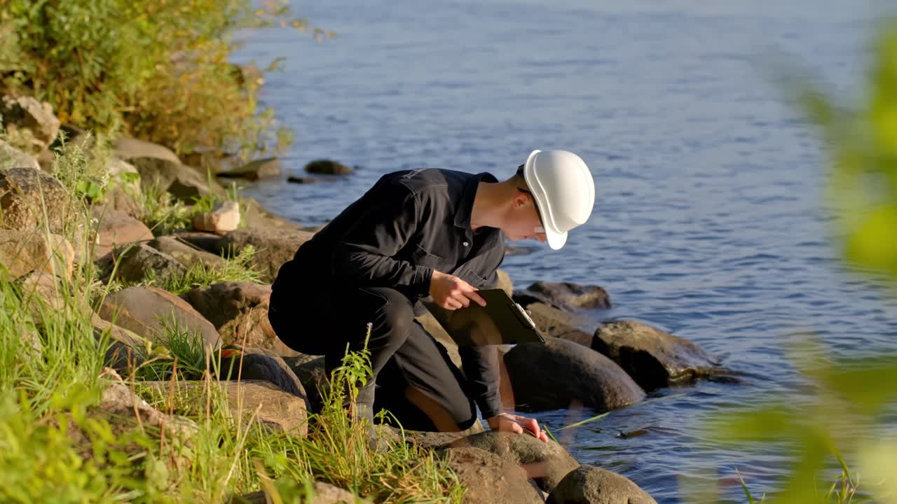 Scientist courching on rocks testing water for pollution analysis in outdoor environmental study
