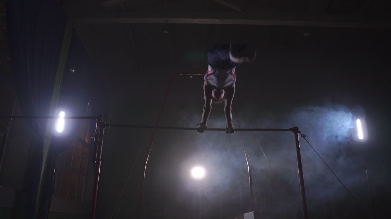 ginnasta su uno sfondo scuro sulla barra trasversale esegue giri e salti sopra se stesso in aria in slow motion e intorno al fumo