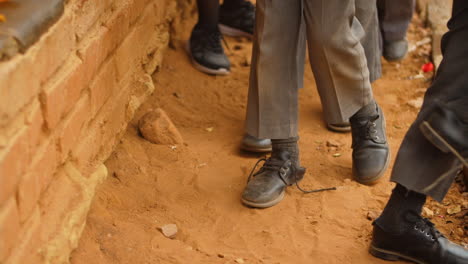 zapatos escolares de los alumnos rurales africanos que esperan en la fila