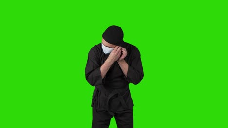 video de un hombre con traje negro ninja vistiendo máscara médica