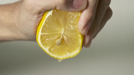 squeezing lemon juice from juicy fresh cut lemon with yellow peel and white rind in slow motion