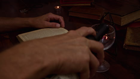 the man reads an old book, pours red wine into the glass