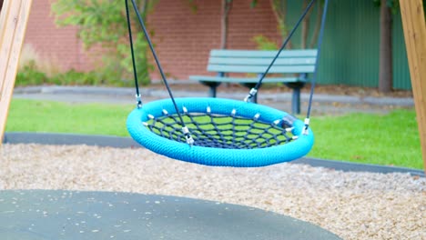 niños pequeños se balancean agitando en el patio de recreo de los niños con el poco día de lluvia y viento débil