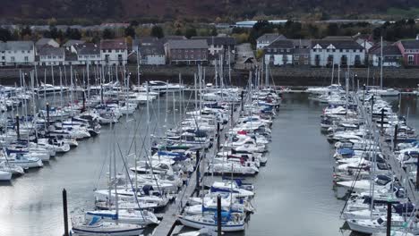 Scenic-luxurious-waterfront-harbour-apartment-village-yachts-and-sailboats-under-mountain-coastline-slow-pull-back-aerial-view