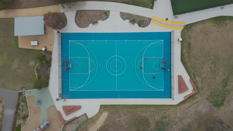 Smooth-drone-accent-while-young-people-play-basketball-with-their-friends-on-a-blue-court