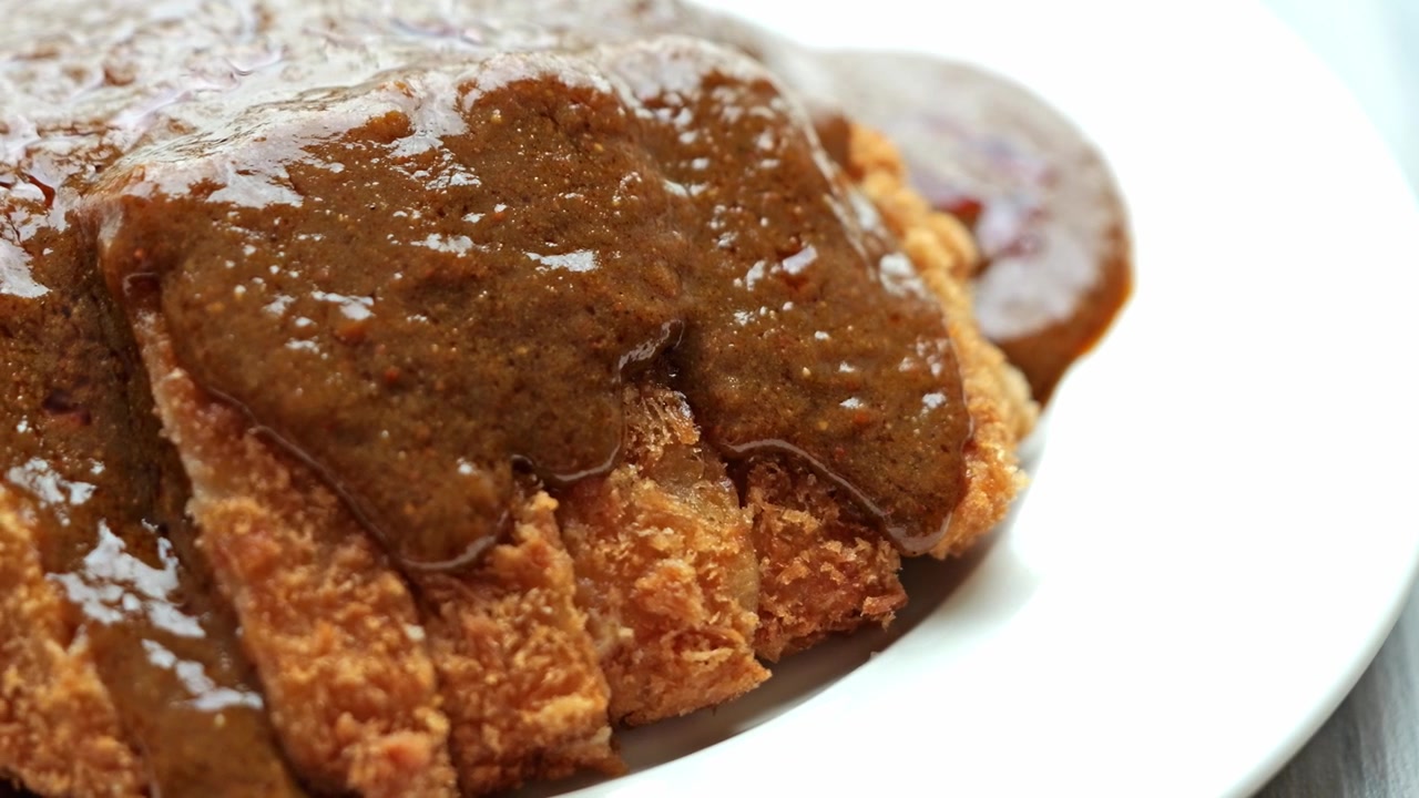 Close-up of crispy pork tonkatsu served with steamed rice, soft egg, and rich Japanese curry sauce, creating a hearty and appetizing comfort meal.