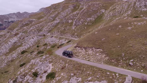 camper van driving through durmitor national park montenegro during cloudy day, aerial