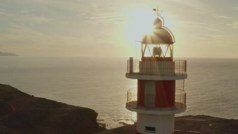 tiro de drone de un faro con sol y océano en el fondo