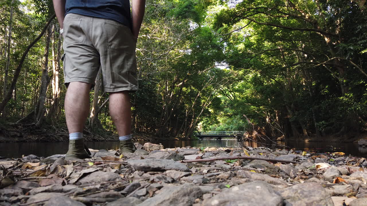 walking in front of camera to enjoy view of beautiful creek