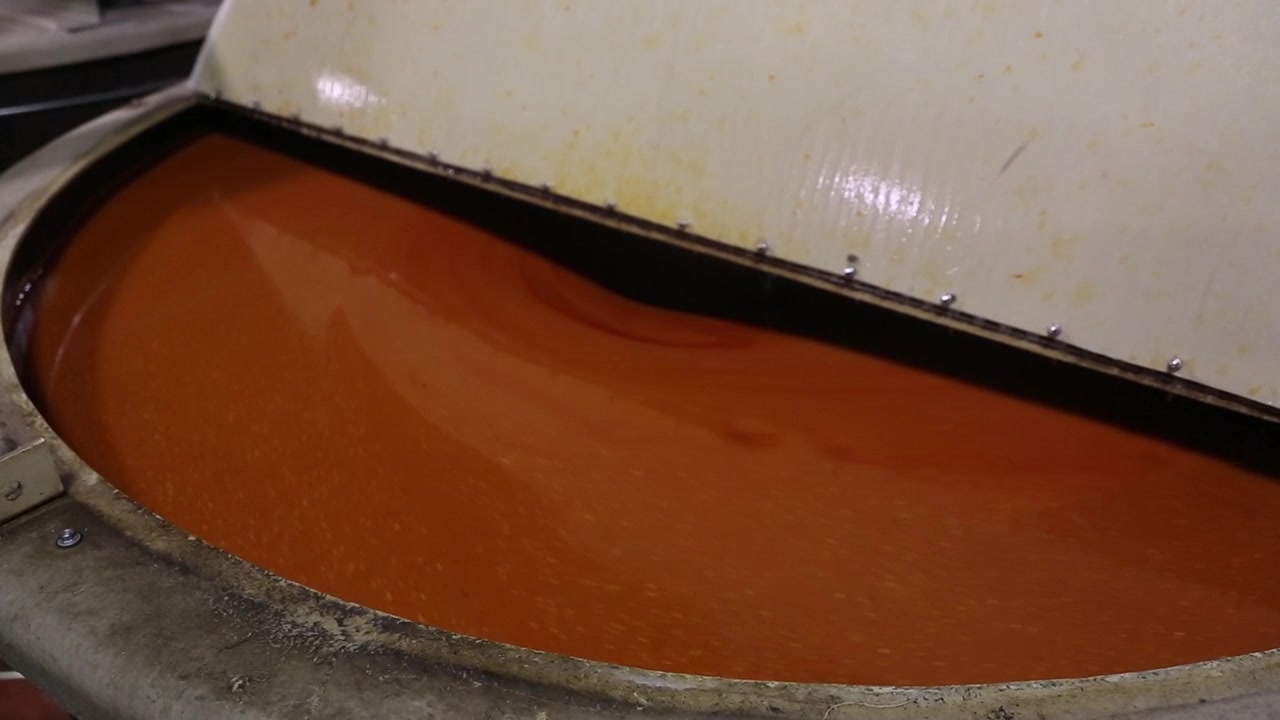 Factory mixing of tabasco pepper sauce. Orange - red abstract swirl.