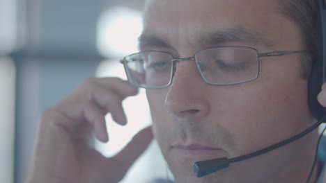 ernstes gesicht eines männlichen callcenter-mitarbeiters, der ein headset aufsetzt