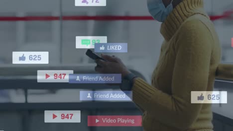 Animation-Von-Social-Media-Symbolen-über-Einer-Afroamerikanischen-Frau-Mit-Gesichtsmaske-Und-Smartphone