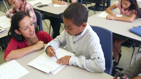 Teacher-helps-schoolboy-in-class,-elevated-zoom,-shot-on-R3D