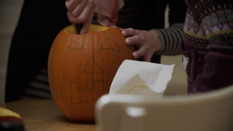 two young kids removing the seeds from a pumpkin for halloween