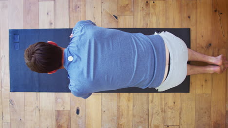 Overhead-View-Of-Man-Doing-Yoga-On-Wooden-Floor