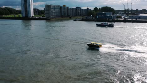 the drone is following a watertaxi going around it in rotterdam the netherlands aerial footage 4k