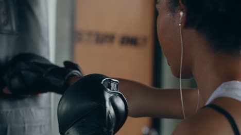 4k healthy african woman listening to the music from earphones while do boxing exercise at gym.