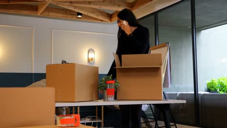 Front-view-of-young-mixed-race-business-colleagues-unpacking-cardboard-boxes-in-modern-office-4k