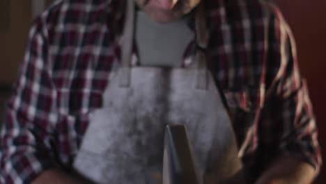 Primer-Plano-De-Un-Fabricante-De-Cuchillos-Masculino-Caucásico-En-El-Taller-Con-Gafas-Y-Lijadora